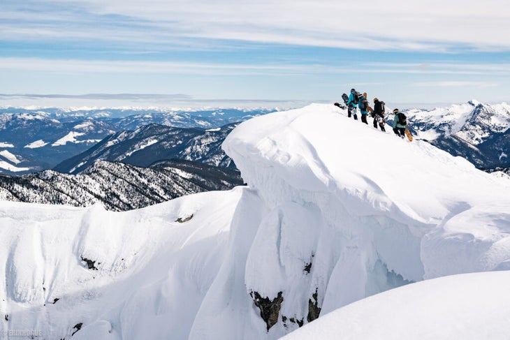 Wide landscape photo of snowboarders climbing a mountain