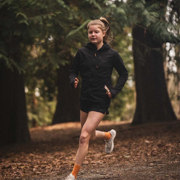 Elite runner Allie Ostrander runs in the forest with a black jacket