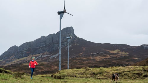 Sarah Boden, a trail runner and sheep farmer, runs in front of a wind turbine