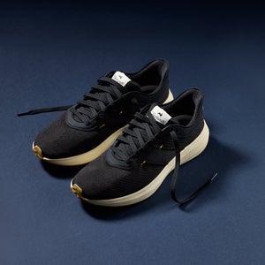 A black pair of running shoes sits diagonal on a blue background