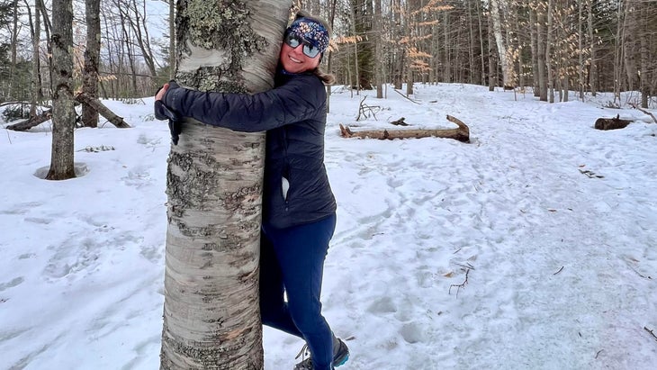 woman hugging tree in winter