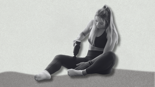 a person using a massage gun on a grey background