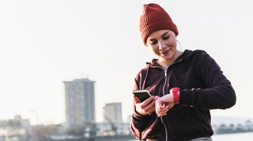 Woman looks at her watch during an outdoor workout while cycle syncing