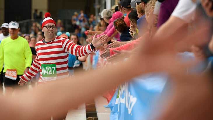 A man high-fives the crowd in a Waldo costume.