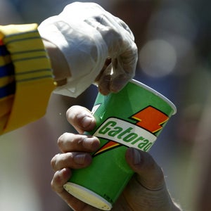 A detail shot of a volunteer as he hads a Gatorade refreshment cup to a runner as he passes through a water station in the town of Natick during the Boston Marathon