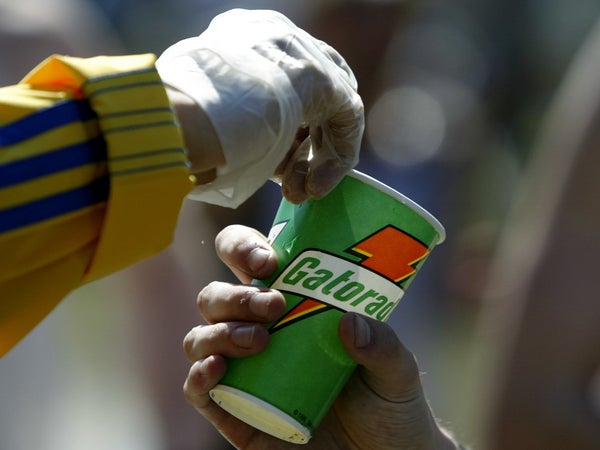 A detail shot of a volunteer as he hads a Gatorade refreshment cup to a runner as he passes through a water station in the town of Natick during the Boston Marathon