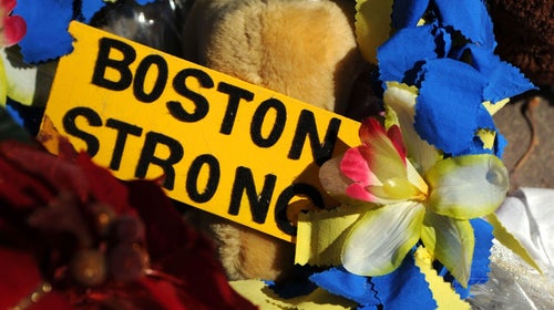 A yellow sign that says Boston Strong surrounded by yellow and blue flowers