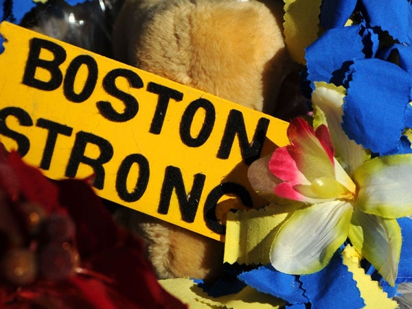 A yellow sign that says Boston Strong surrounded by yellow and blue flowers