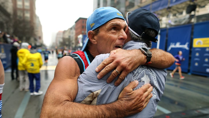 A Boston Marathon finisher in a backwards cap hug another person after finishing the Boston Marathon