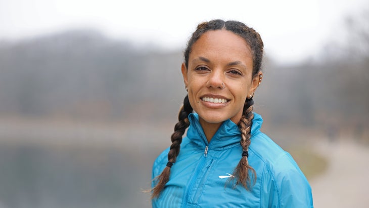 Runner in a blue jacket and braided hair.