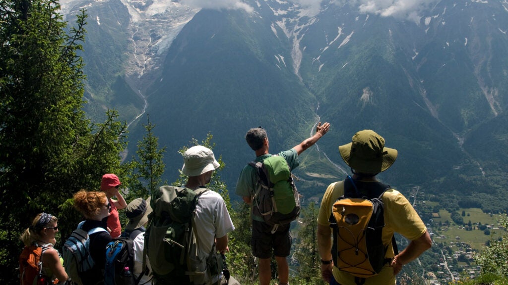 Professional guide leading group of hikers through mountain terrain during guided outdoor adventure