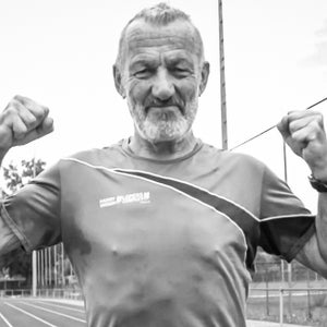 A masters runner shows muscles on a track in a black and white photo