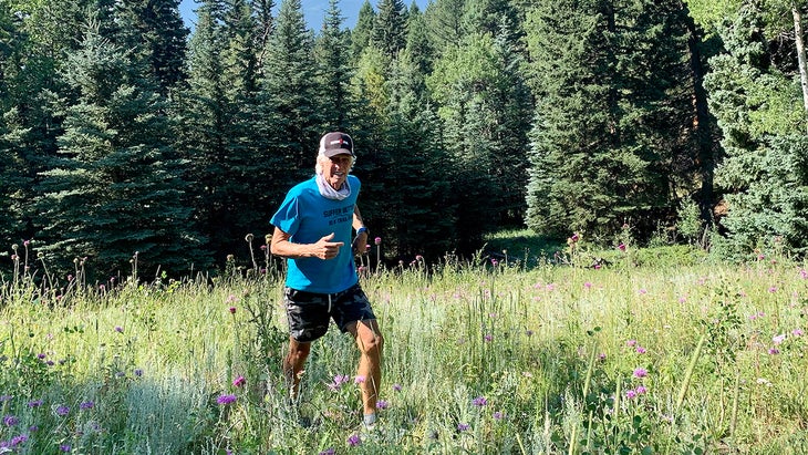 Macy is in a blue shirt and he is running in the forest