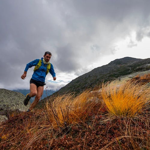 Man running uphill with grasses and stormy weather