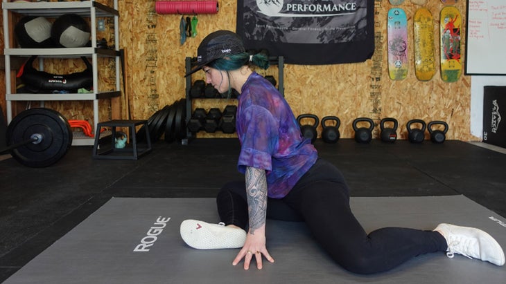 One of the mobility exercises for knee pain. A woman is in a seated position with one leg and front and one leg behind her, with both legs angled at 90 degrees.