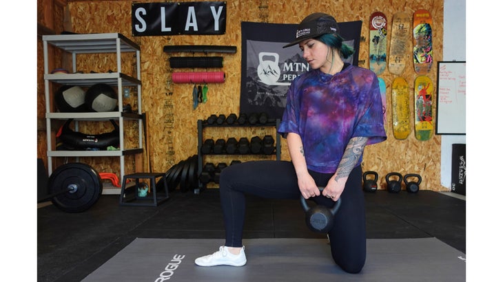 One of the mobility exercises for knee pain. A woman sits in a half kneeling position while holding a kettlebell.