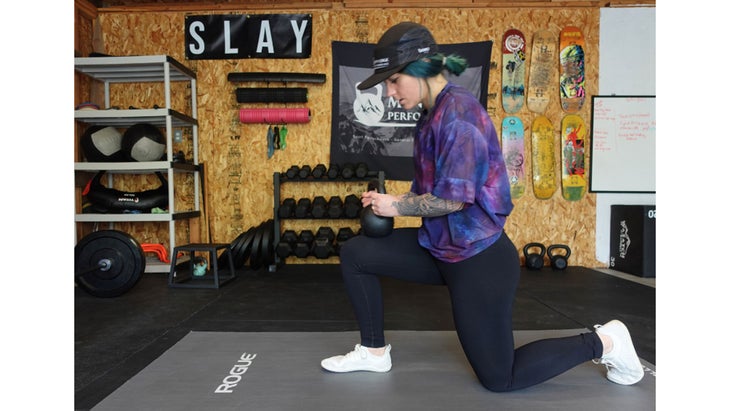 One of the mobility exercises for knee pain. A woman in a half kneeling position holds a kettlebell.