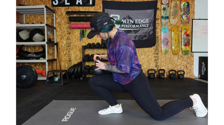 One of the mobility exercises for knee pain. A woman in a kneeling position holds a kettlebell and leans forward.