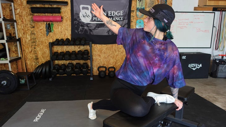 One of the mobility exercises for knee pain. A woman in pigeon pose with her front leg propped on a bench.