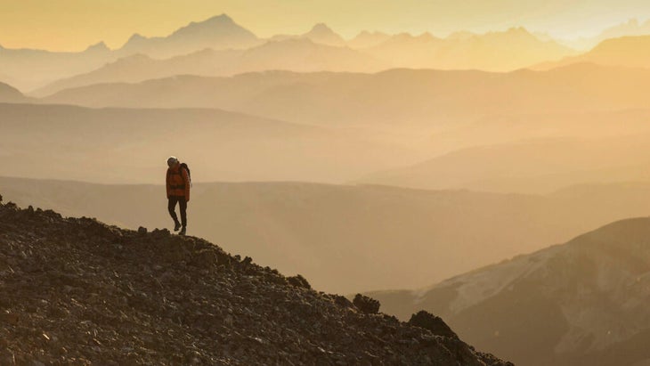 A person walking on a mountainous landscape at golden hour