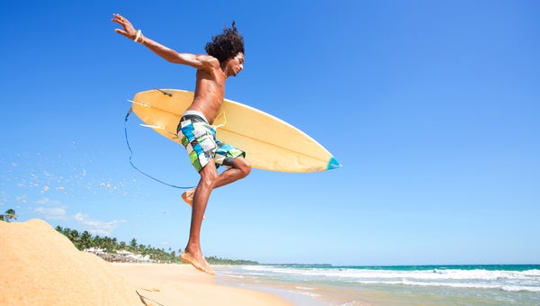 Surfer running towards the water wearing board shorts