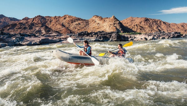 A couple paddling down some river rapids