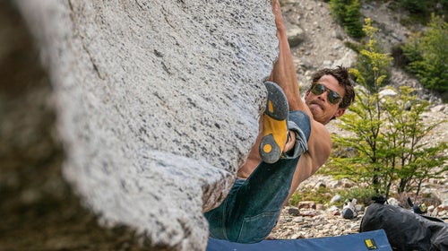 Climber bouldering with yellow climbing shoes