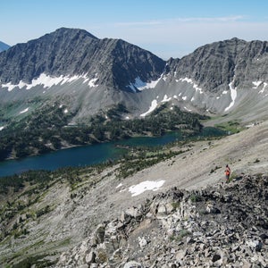 A person in red stands amidst the crazy mountains and a high alpine lake in Montana