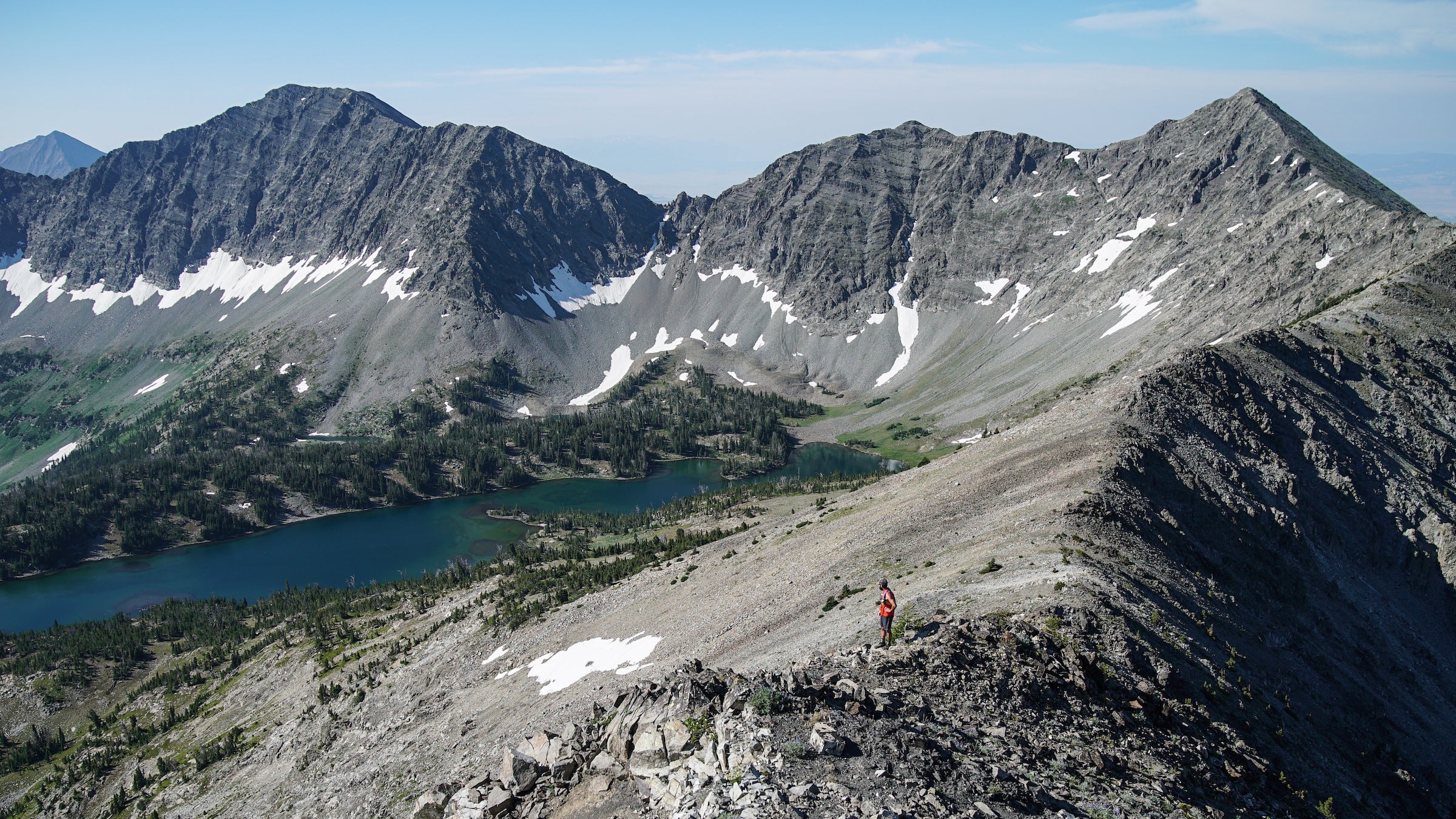 A person in red stands amidst the crazy mountains and a high alpine lake in Montana