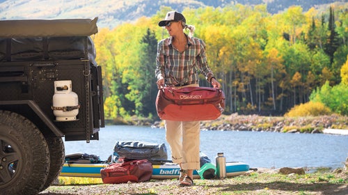 Meagan Tougher-Preece unloads her stand up paddle board equipment from an off-road trailer in a dirt parking lot on the shore of an alpine lake in Telluride, Colorado