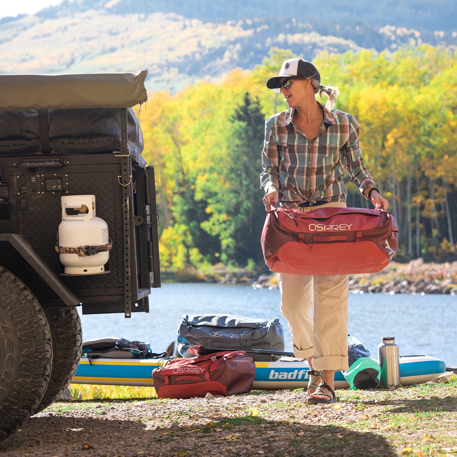 Meagan Tougher-Preece unloads her stand up paddle board equipment from an off-road trailer in a dirt parking lot on the shore of an alpine lake in Telluride, Colorado