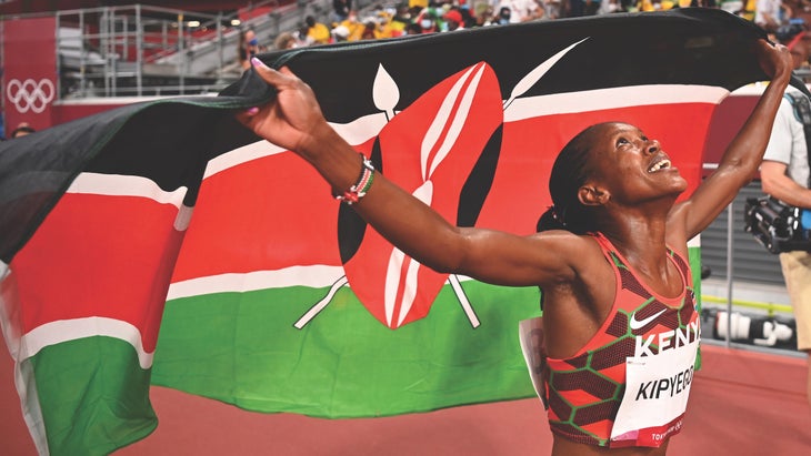 A Kenyan runner holds up a green black and red flag at the Olympics