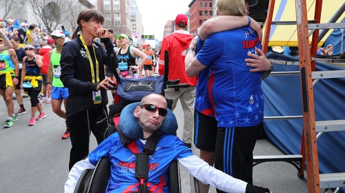 A man is assisted in a wheelchair to finish the Boston Marathon