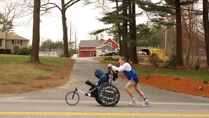A man pushes his son uphill at the Boston Marathon