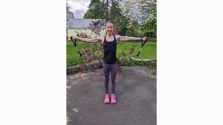 Woman does lateral raises as part of a resistance band arm workout