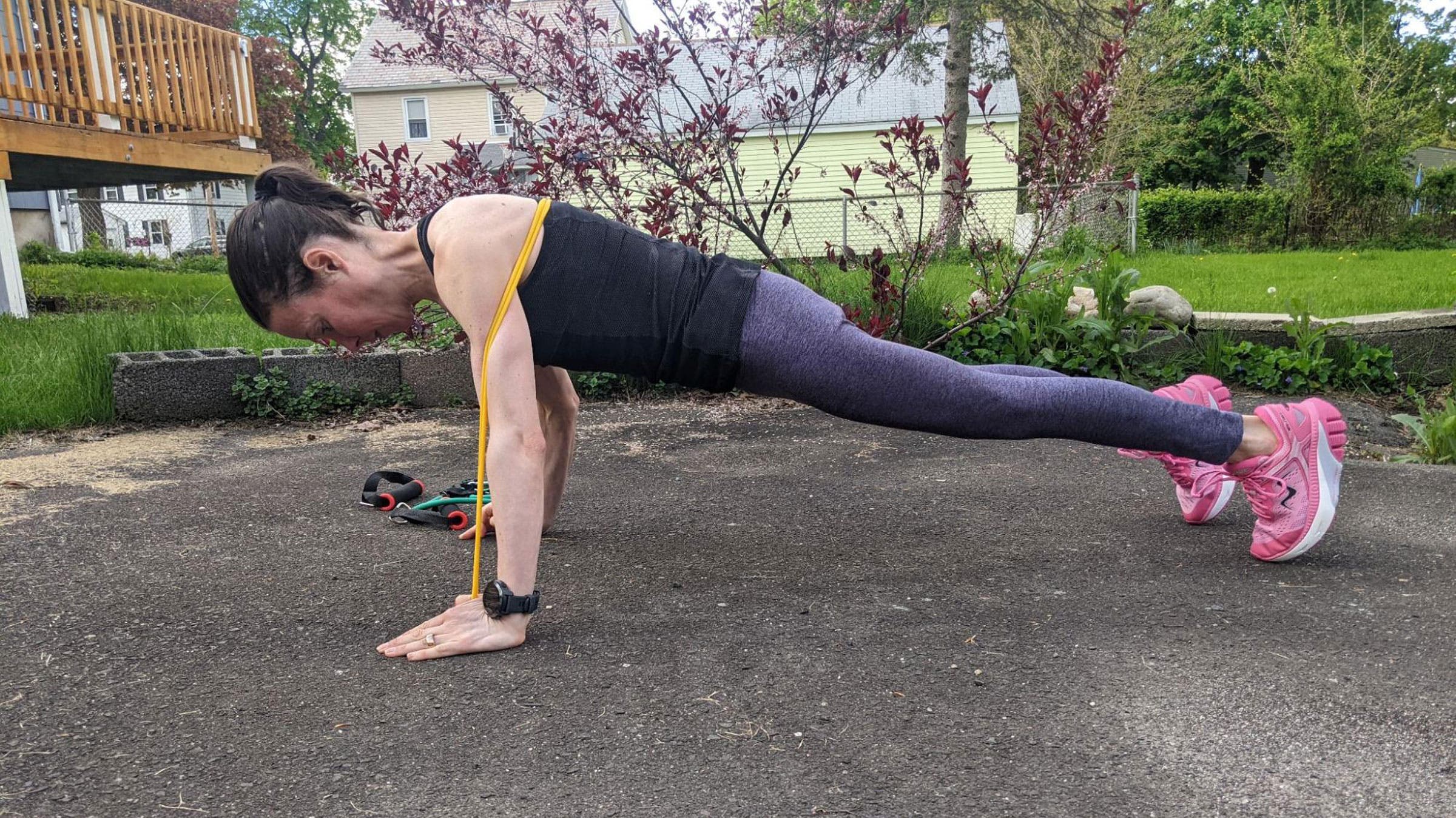 Woman demonstrates a push-up for a resistance band arm workout