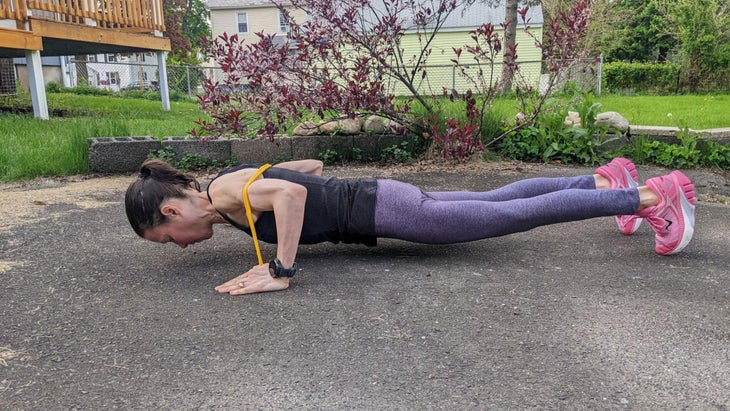 Woman demonstrates a push-up for a resistance band arm workout