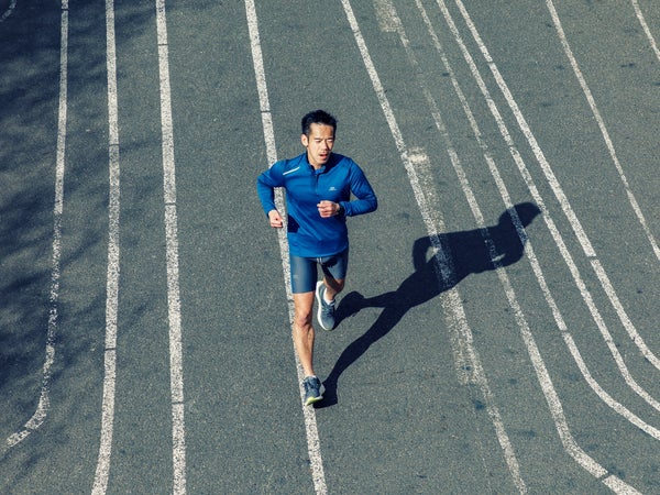 A man runs along strips of white paint on a road