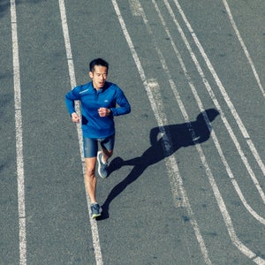 A man runs along strips of white paint on a road
