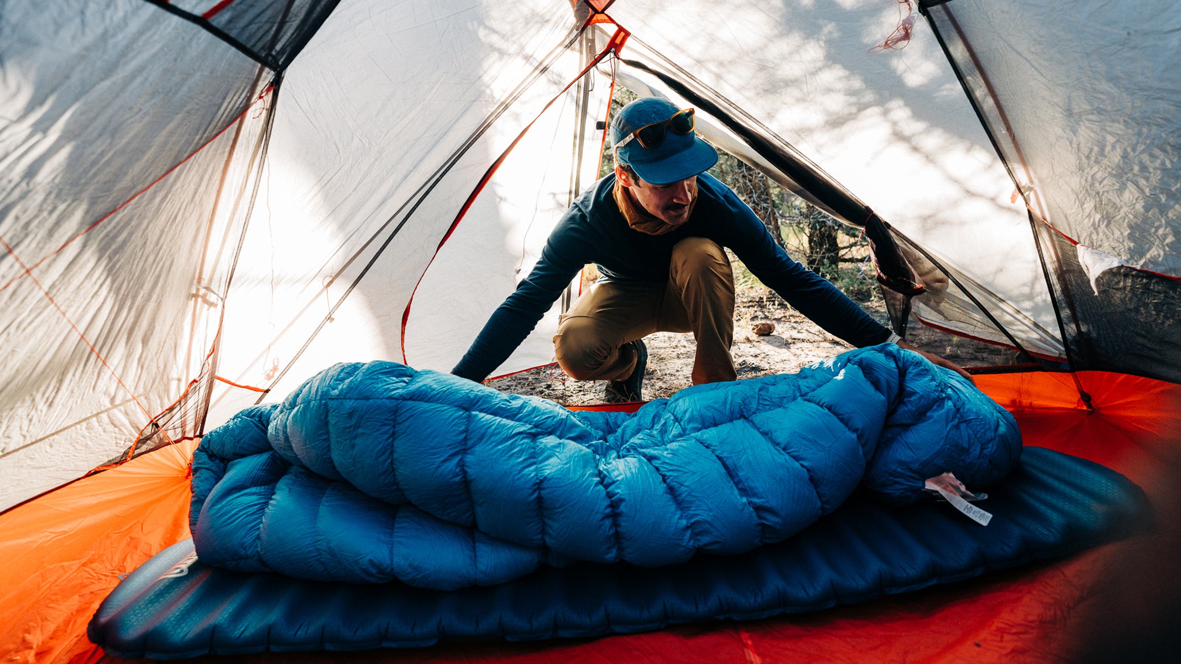 rolling out a sleeping bag in a tent