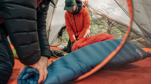 rolling up a sleeping pad in a tent