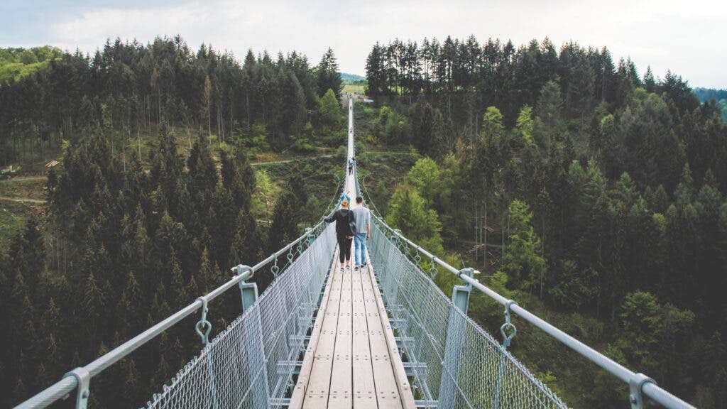 A couple walks across a suspension bridge in Portugal