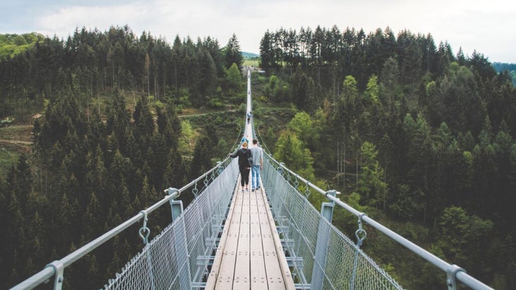 A couple walks across a suspension bridge in Portugal
