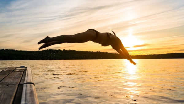 Woman diving into the lake from the dock at a cottage in northern Ontario, Canada near Muskoaka
