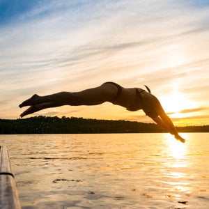Woman diving into the lake from the dock at a cottage in northern Ontario, Canada near Muskoaka