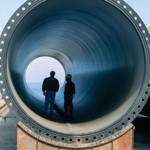 Site workers standing in a section of precast concrete pipe used for transporting water