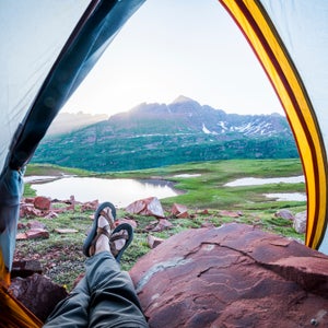View from inside tent of person wearing sandles looking over a lake