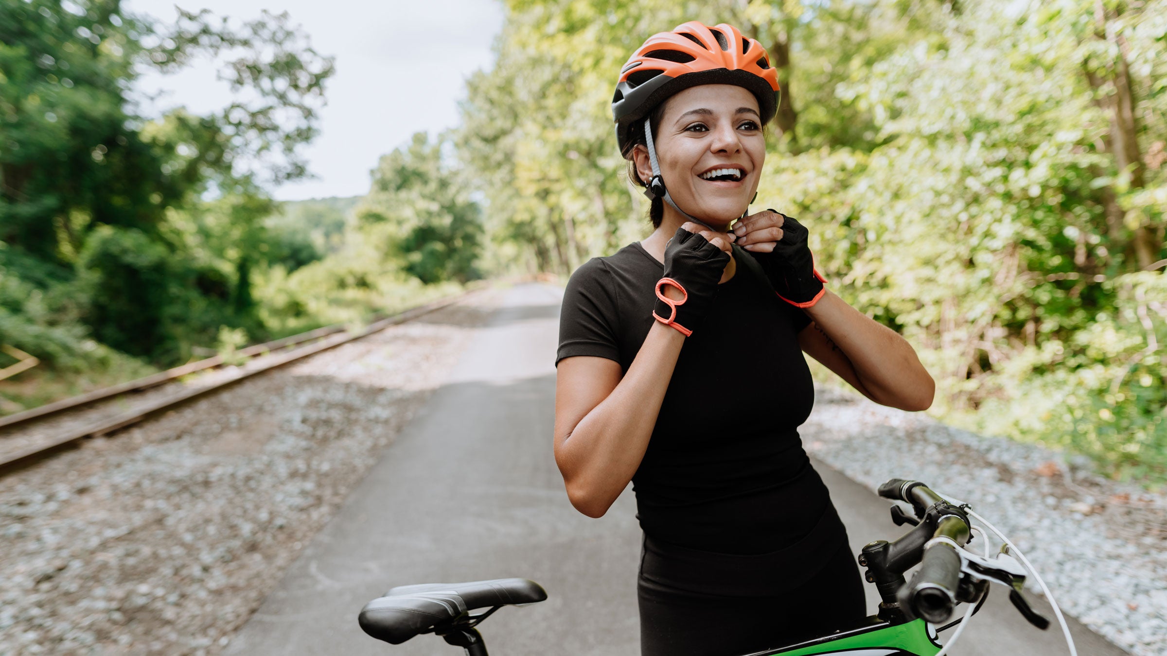 Woman prepares for a bike ride by putting on her helmet
