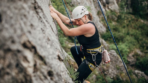 Woman climbs boulder with hypermobility