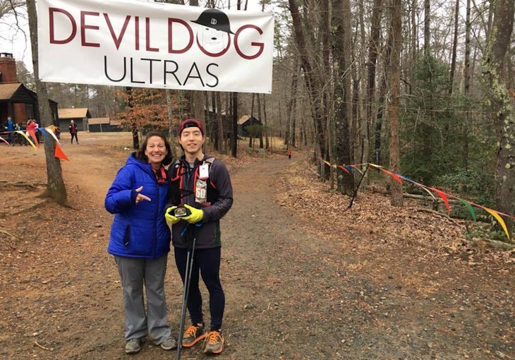 Two runners at the finish line of an ultra, around a brown forest